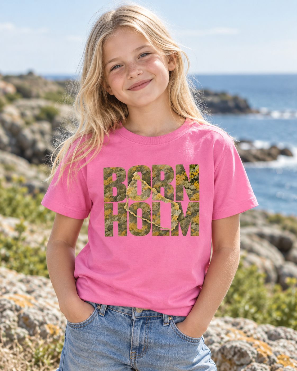 Girl wearing a pink Bornholm T-shirt by the rocky coast